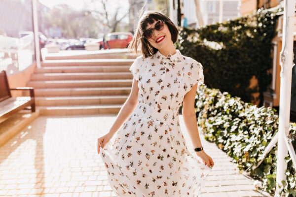Femeie zâmbitoare în rochie florală, ochelari de soare